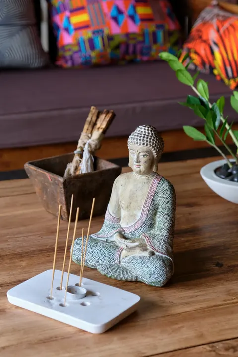 A stone Buddha with incense in the gardens