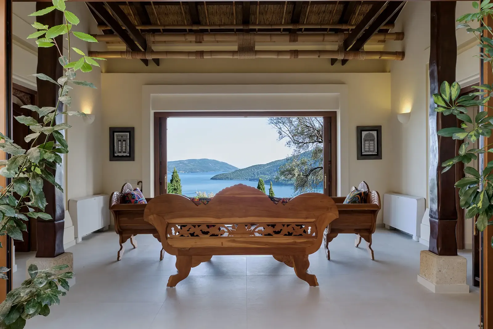 A carved daybed before a window onto the sea and the islands